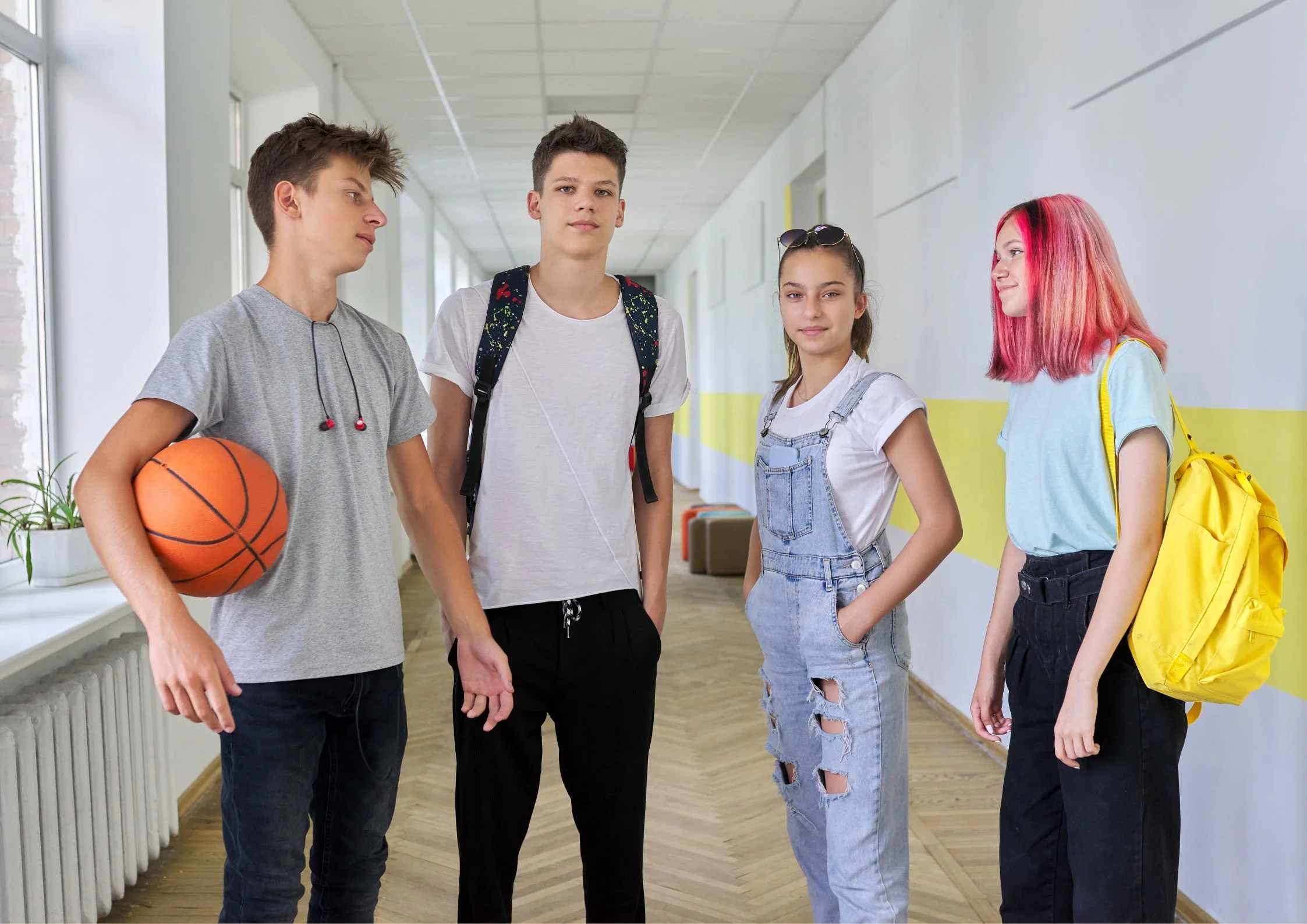 4 teenageři stojí ve škole